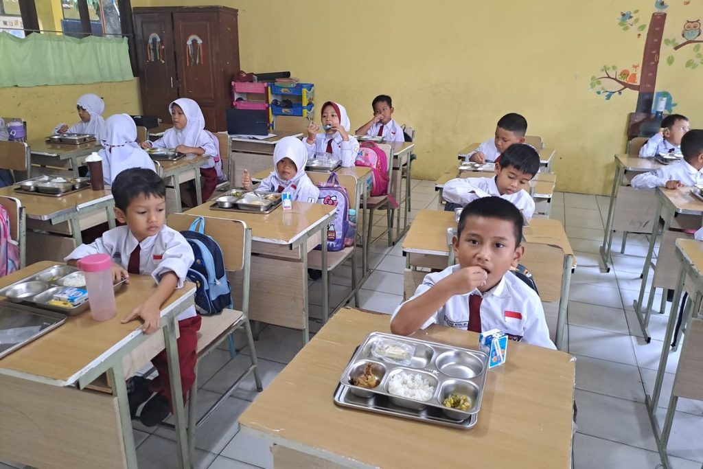 Anak-anak dengan bahagia sedang makan makanan bergizi di kafetaria sekolah yang berwarna-warni dengan buah-buahan, sayuran, dan piring seimbang yang mempromosikan nutrisi sehat.